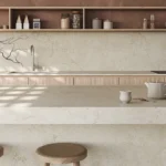 Caesarstone ICON 8252 Sedara in Minimalist kitchen with marble countertops, wooden stools, open shelves, and vase with bare branches.