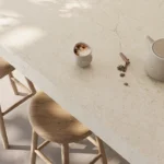 Caesarstone ICON 8252 Sedara light stone countertop with Two wooden stools, a teapot, spices, and a cup.